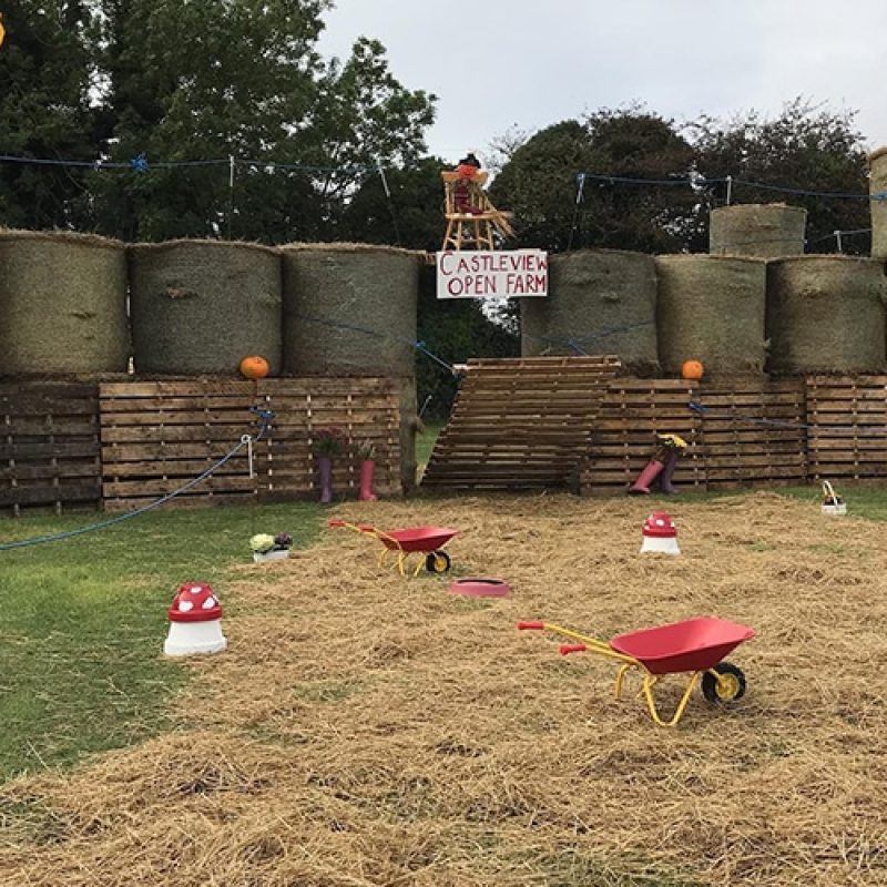 Castleview Open Farm's hay bale castle with flags and red wheelbarrows awaits!.